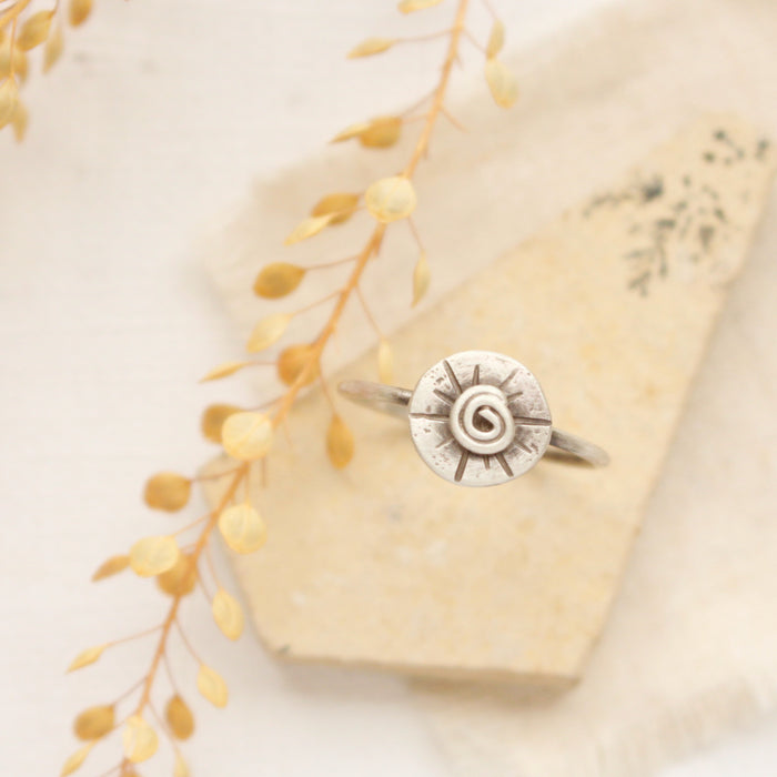 The musana ring styled on a tan rock with dried grass