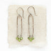 The olivine jade wrapped long forged hoop earrings styled on tan linen