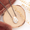 The organic pearl mixed metal necklace styled on wood with orange velvet and dried grass