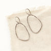 The organic silver hoop earrings styled on tan linen