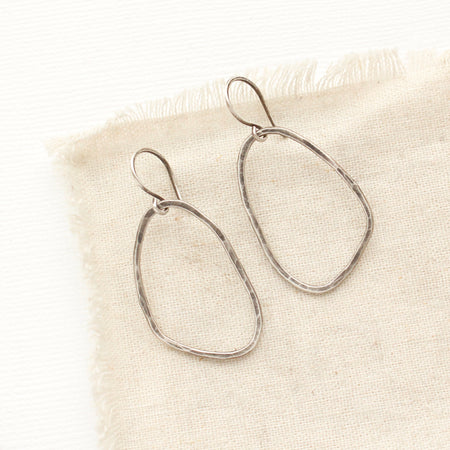 The organic silver hoop earrings styled on tan linen