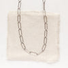 The oxidized silver paperclip necklace styled on tan linen