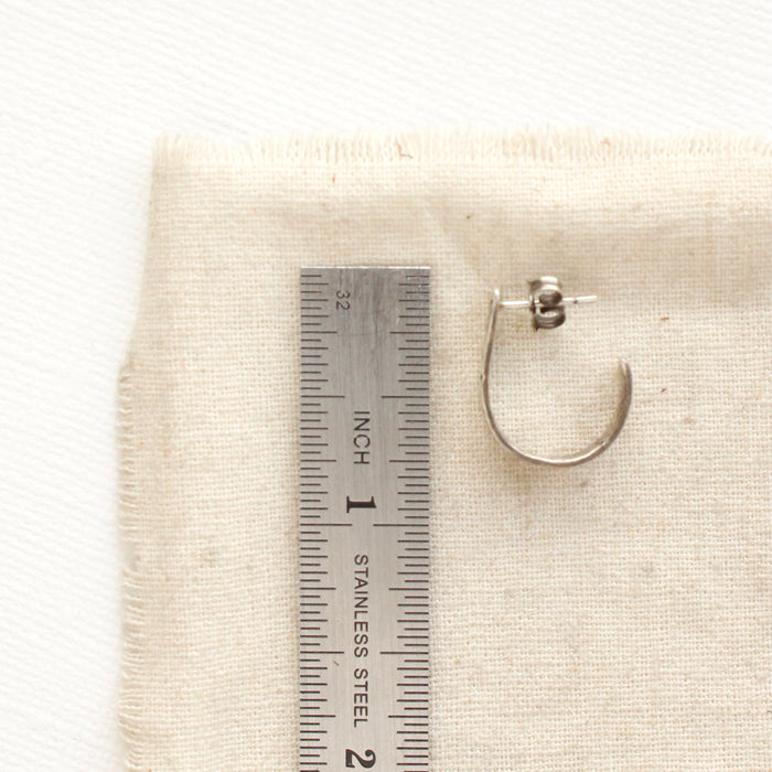 A pakal hoop post earring next to a ruler for size reference