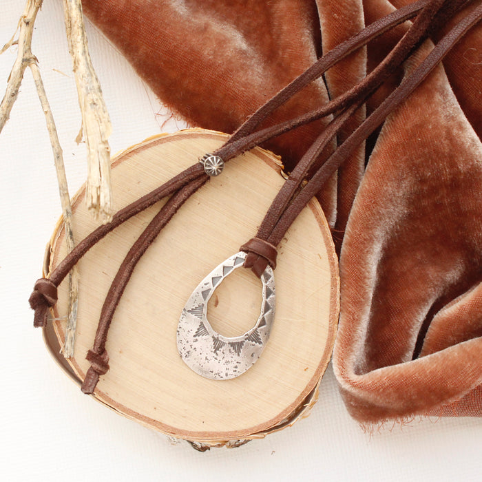 The pakal teardrop adjustable leather necklace styled on wood with orange velvet and a stick