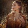 A model wearing the pakal trio turquoise post earrings and matching necklace in a grassy field