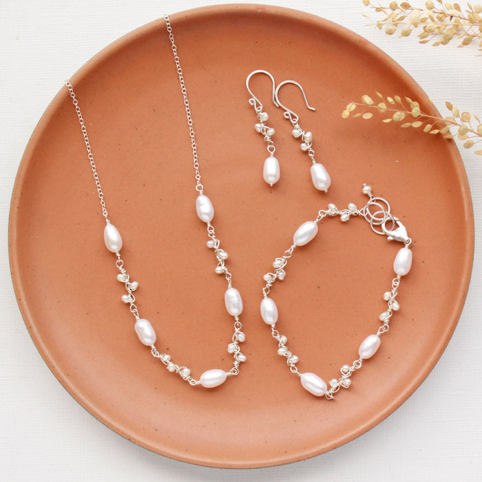The pearl bud vine earrings styled on an orange plate with the matching bracelet and necklace 