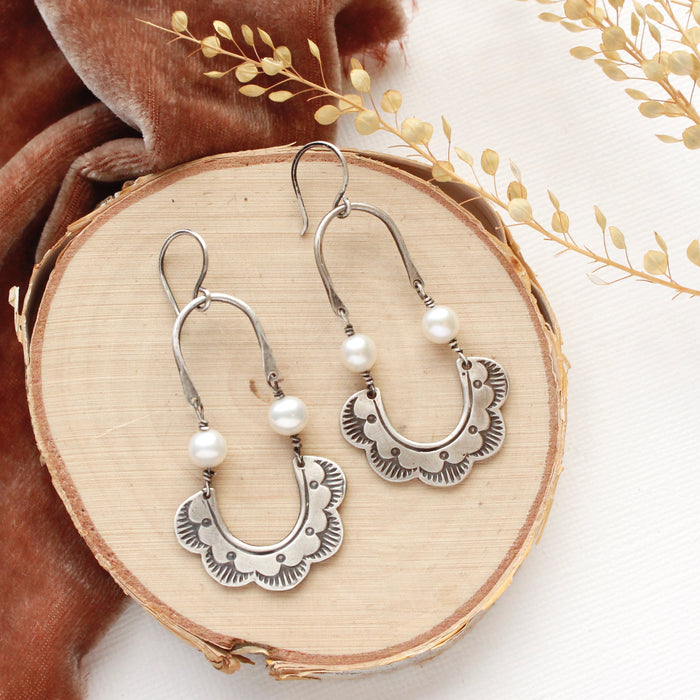 The pearl columbine hoop earrings styled on wood with orange velvet and dried grass