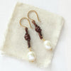 The pearl and leather earrings styled on tan linen