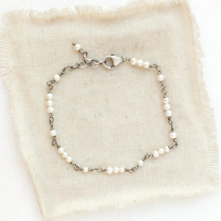 The pearl wrapped bracelet styled on tan linen