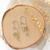 The peridot trio hoop earrings styled on wood with dried grass