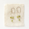 The peridot trio hoop earrings styled on tan linen