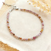 The violet bracelet styled on a tan rock with linen and dried grass