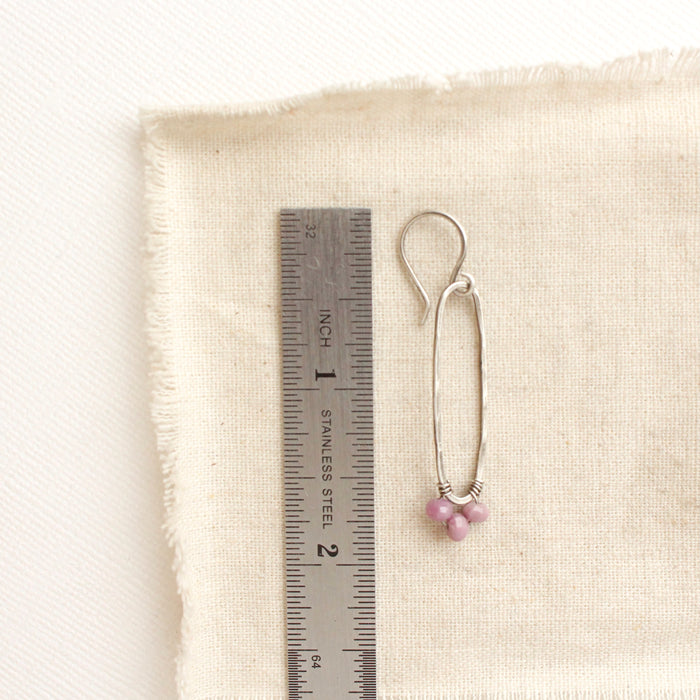 A phosphosiderite wrapped long hoop earring next to a ruler for size reference