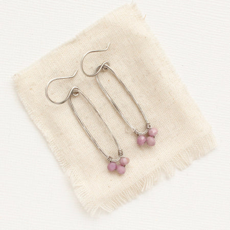 The phosphosiderite wrapped long hoop earrings styled on tan linen