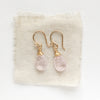 The morganite drop earrings styled on tan linen