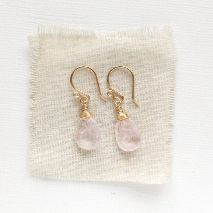 The morganite drop earrings styled on tan linen