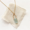 The pinned aquamarine gold necklace styled on tan linen