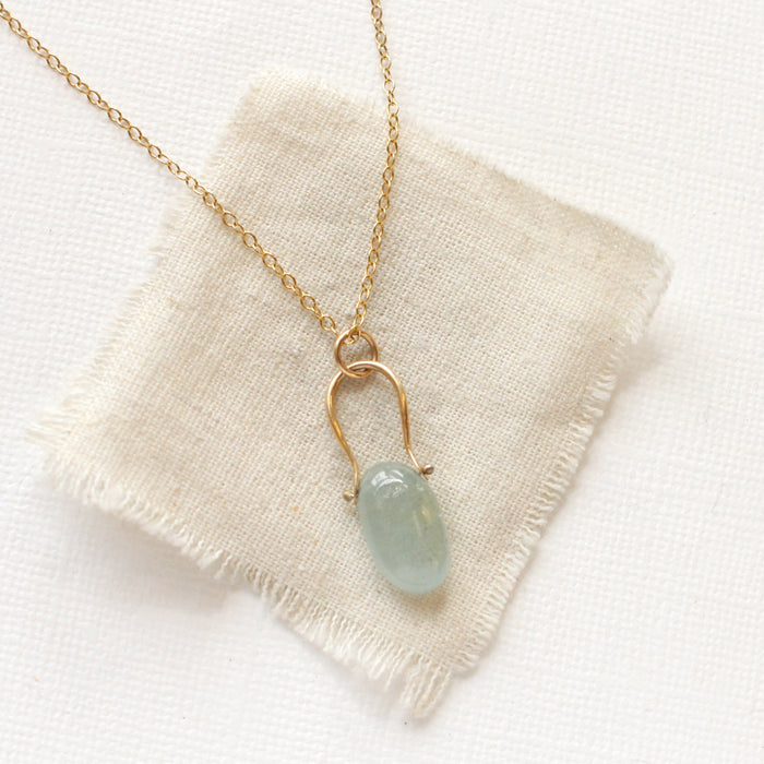 The pinned aquamarine gold necklace styled on tan linen