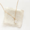 The pinned gold herkimer diamond necklace styled on tan linen