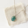 The prong set emerald necklace styled on tan linen
