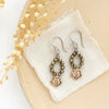 The bronze mini cactus flower and pyrite earrings styled on a tan plate with linen and dried grass