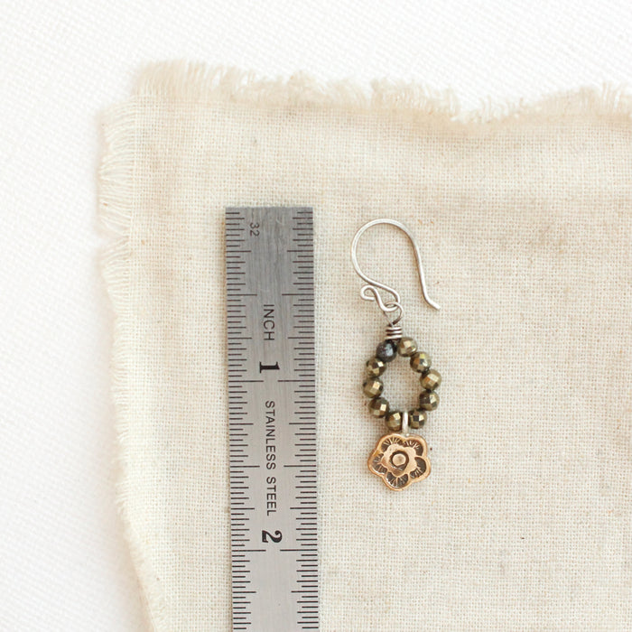 A bronze mini cactus flower and pyrite earring next to a ruler for size reference