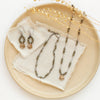 The bronze mini cactus flower and pyrite earrings styled on a tan plate with the matching necklace and bracelet