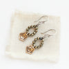 The mini bronze cactus flower & pyrite hoop earrings styled on tan linen