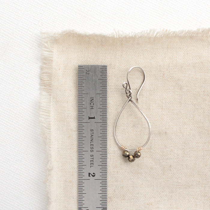 A pyrite wrapped teardrop hoop styled next to a ruler for size reference