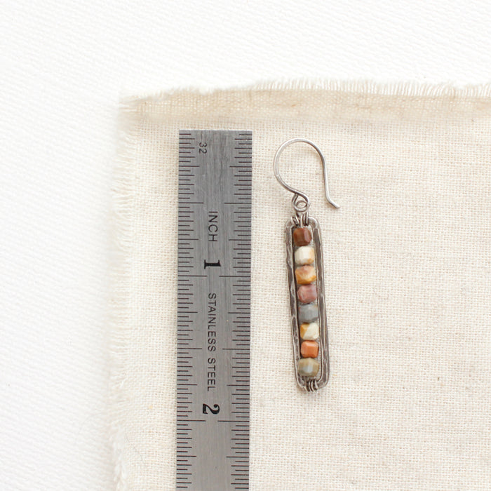 A rainbow agate beaded bar earring next to a ruler for size reference