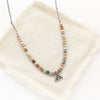 The rainbow agate sun rise charm necklace styled on tan linen