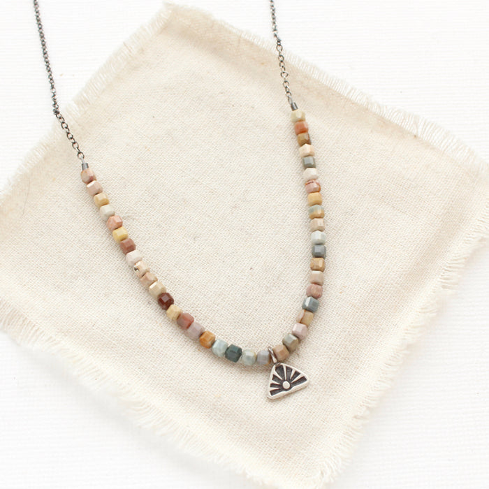 The rainbow agate sun rise charm necklace styled on tan linen