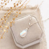 The rainbow moonstone silver bar necklace styled on a white velvet box with linen and dried grass