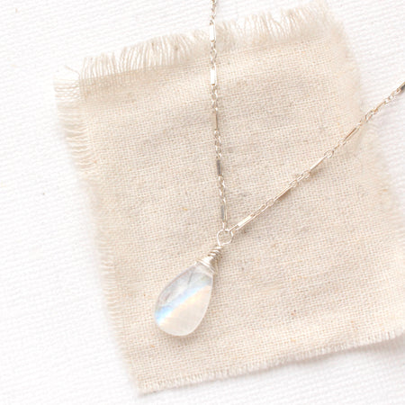 The rainbow moonstone silver bar necklace styled on tan linen