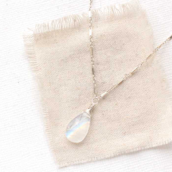 The rainbow moonstone silver bar necklace styled on tan linen