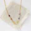 The wrapped gold rainbow necklace styled on tan linen