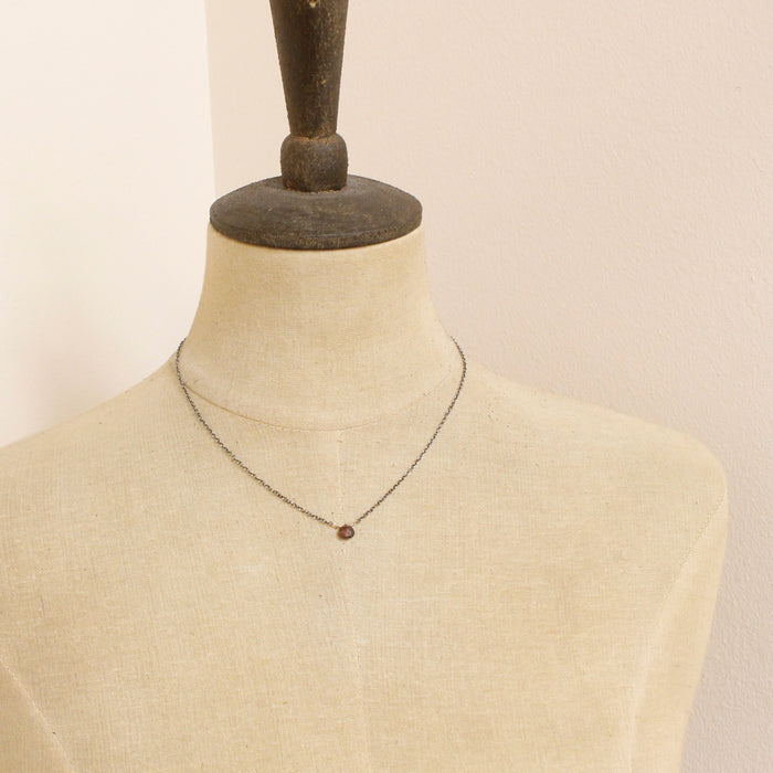 A mannequin wearing the little garnet drop necklace