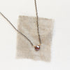 The rhodolite garnet mixed metal necklace styled on tan linen