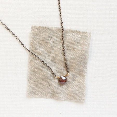 The rhodolite garnet mixed metal necklace styled on tan linen