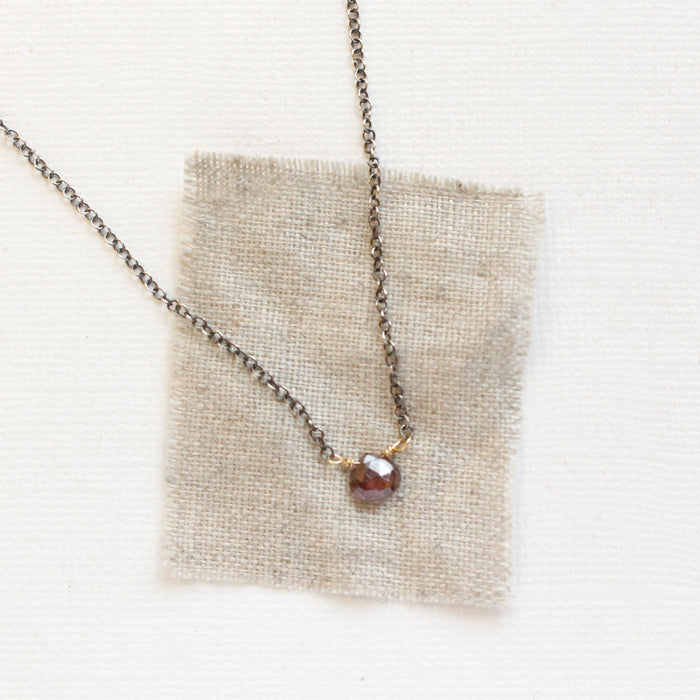 The rhodolite garnet mixed metal necklace styled on tan linen