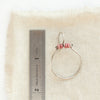 A rhodonite halo hoop earring next to a ruler for size reference