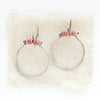 The rhodonite halo hoop earrings styled on tan linen