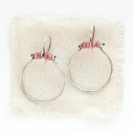 The rhodonite halo hoop earrings styled on tan linen