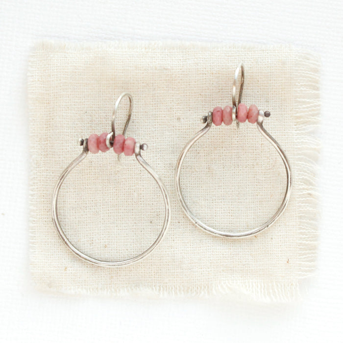 The rhodonite halo hoop earrings styled on tan linen