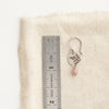 A rhodonite sprout earring next to a ruler for size reference