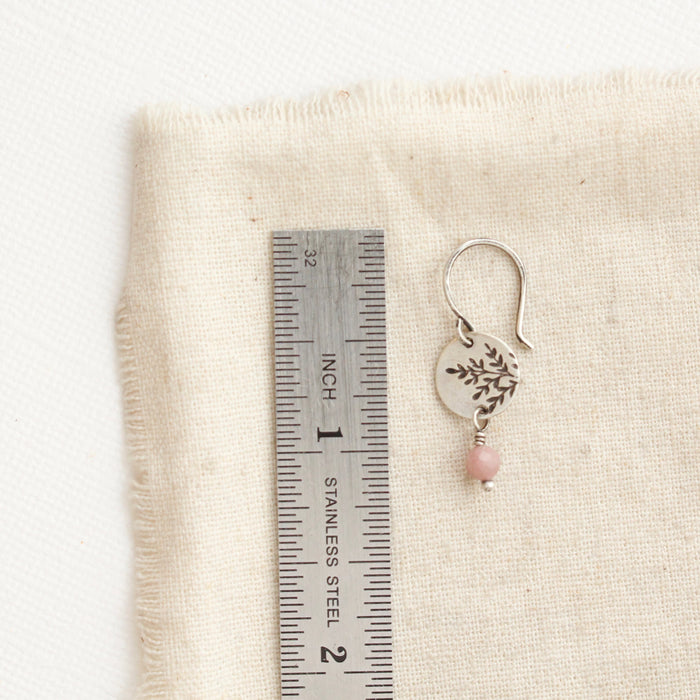A rhodonite sprout earring next to a ruler for size reference