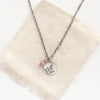 The rhodonite and sprout charm necklace styled on tan linen