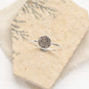 The roma embossed silver stacking ring styled on a tan rock with tan linen