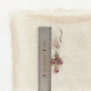 A mini cactus flower violet dangle earring next to a ruler for size reference