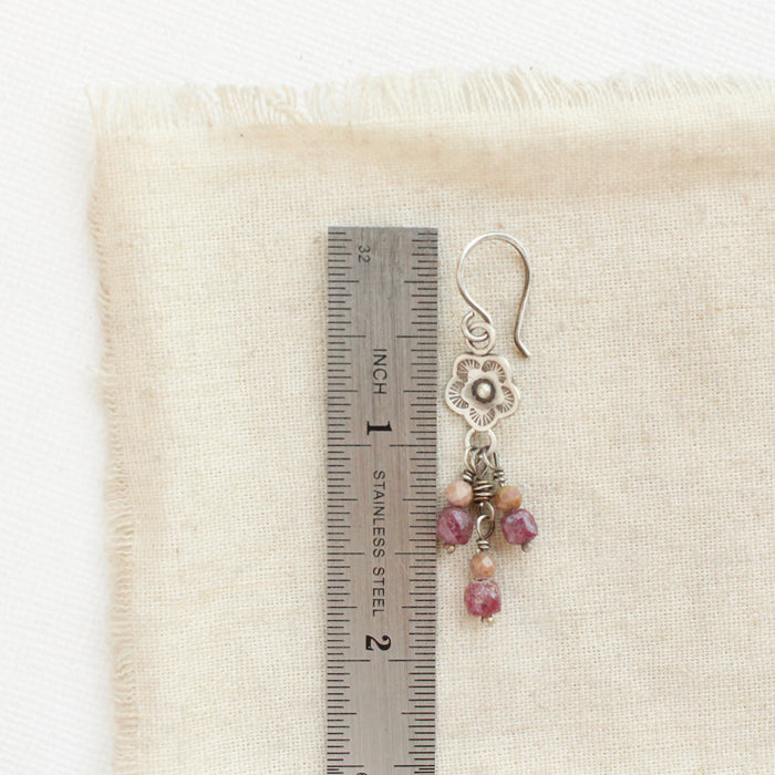 A mini cactus flower violet dangle earring next to a ruler for size reference